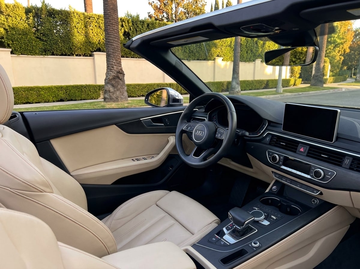 Beige leather cabin of the black Audi A5 Cabriolet, seen across from the passenger seat with the roof down