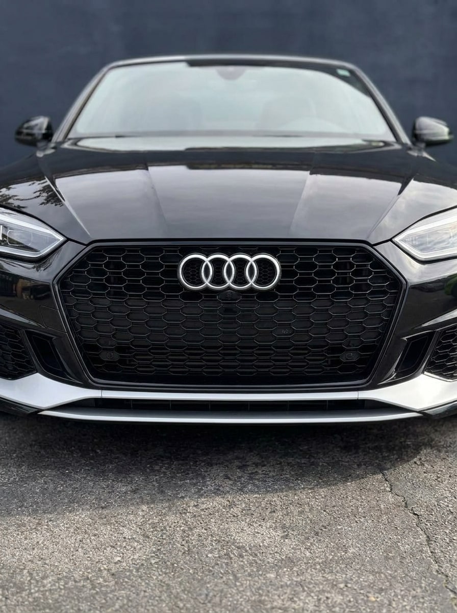 Honeycomb RS grille and four-ring emblem across the front of the black Audi A5