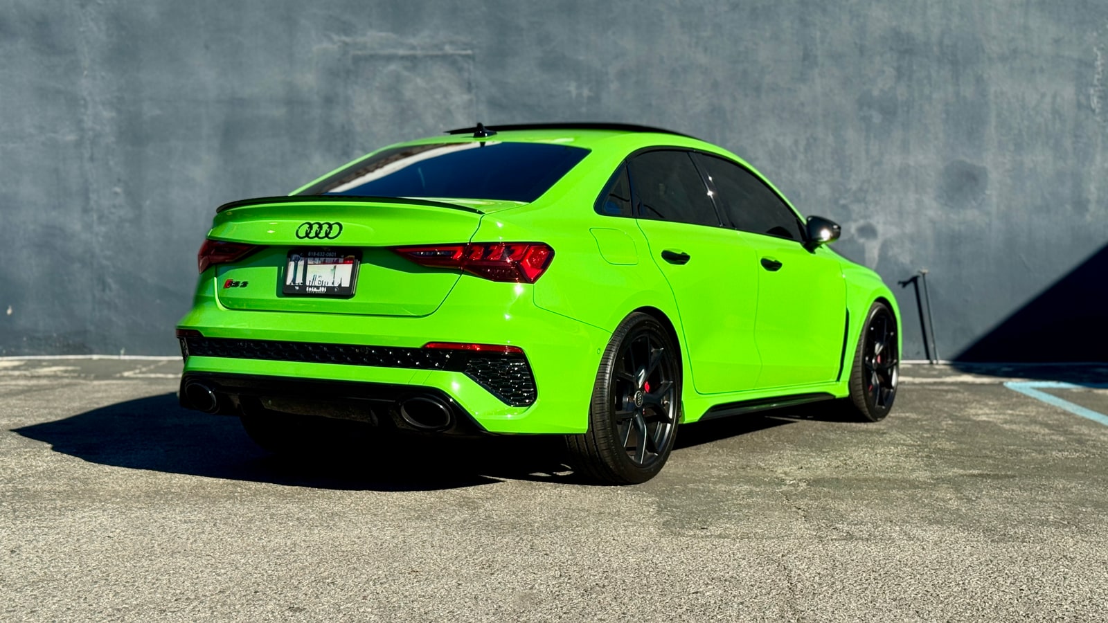Rear three-quarter of the green Audi RS 3 showing the oval tailpipes