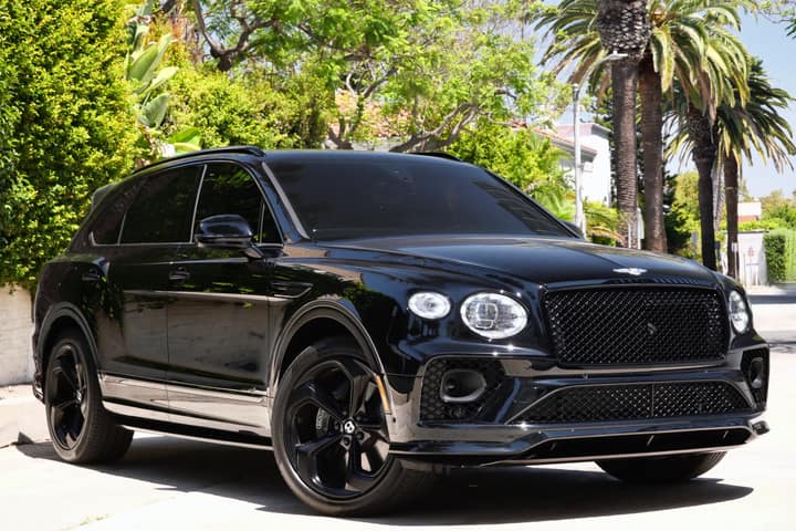 Black Bentley Bentayga parked beneath palm trees