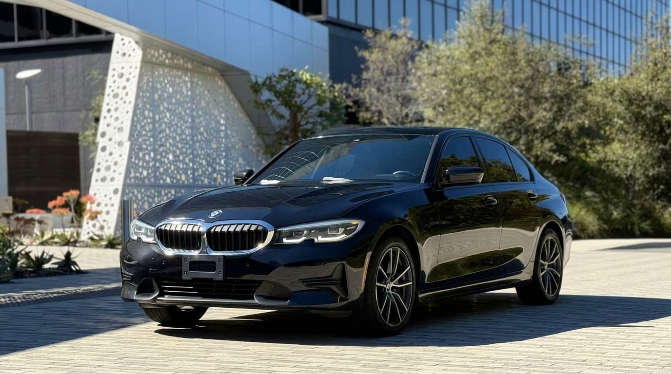 Black BMW 3 Series on a plaza beside a perforated-metal building in Playa Vista, front three-quarter view