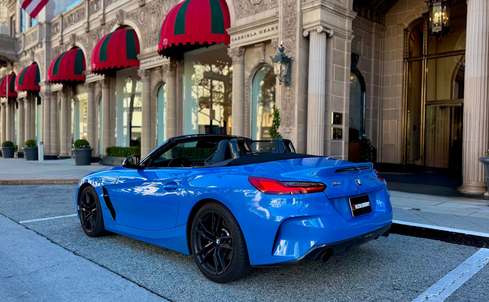 Blue BMW Z4 with the roof down outside a Beverly Hills hotel