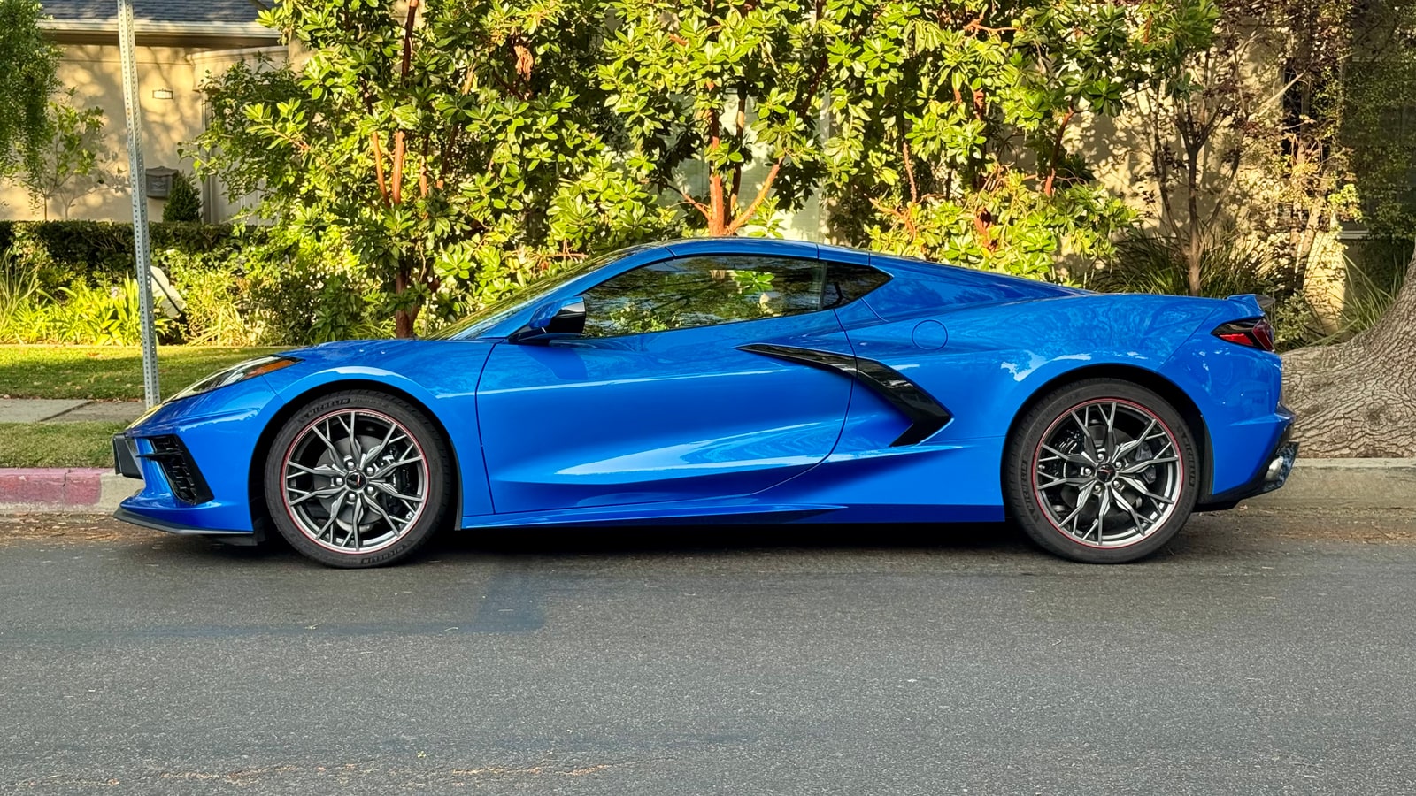 Blue Chevrolet Corvette in profile on a residential street