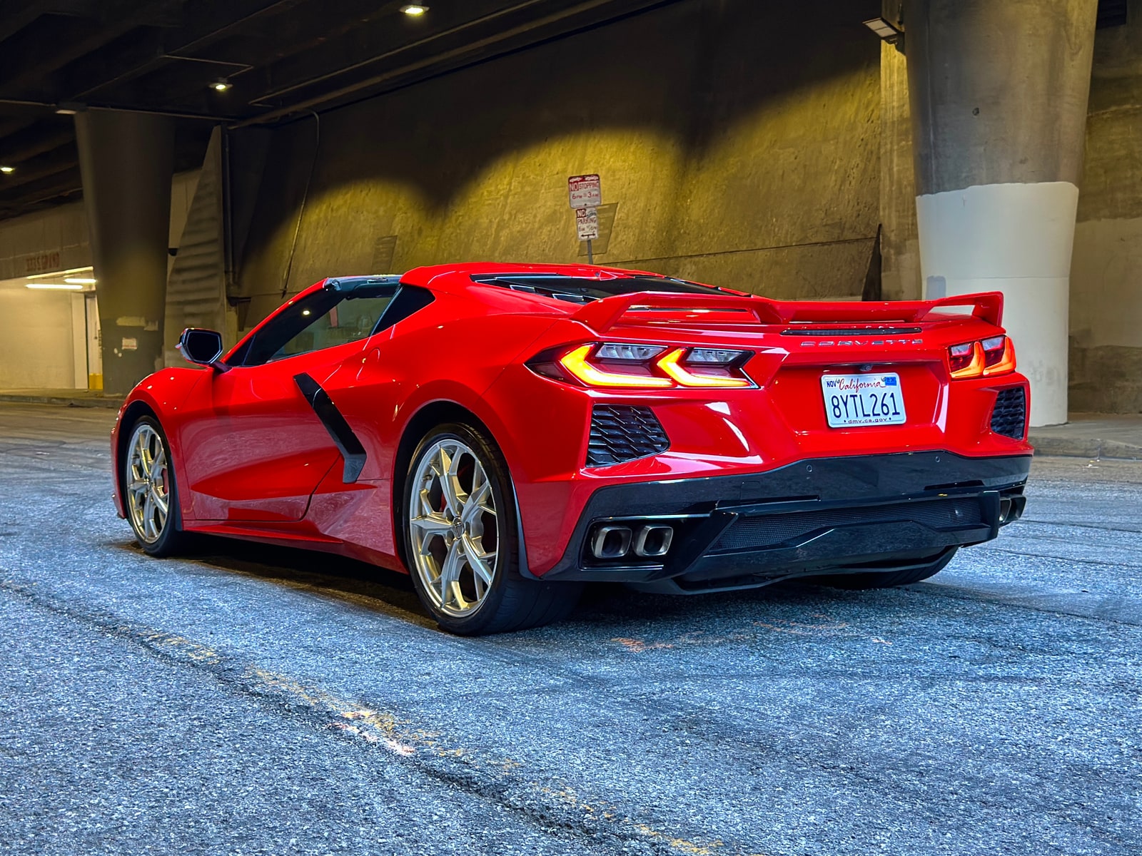 Red Corvette Convertible parked in a concrete structure with the roof down