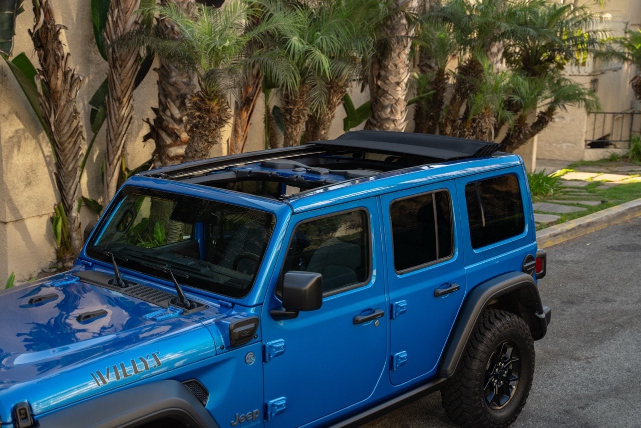 Blue Jeep Wrangler with the roof panels removed