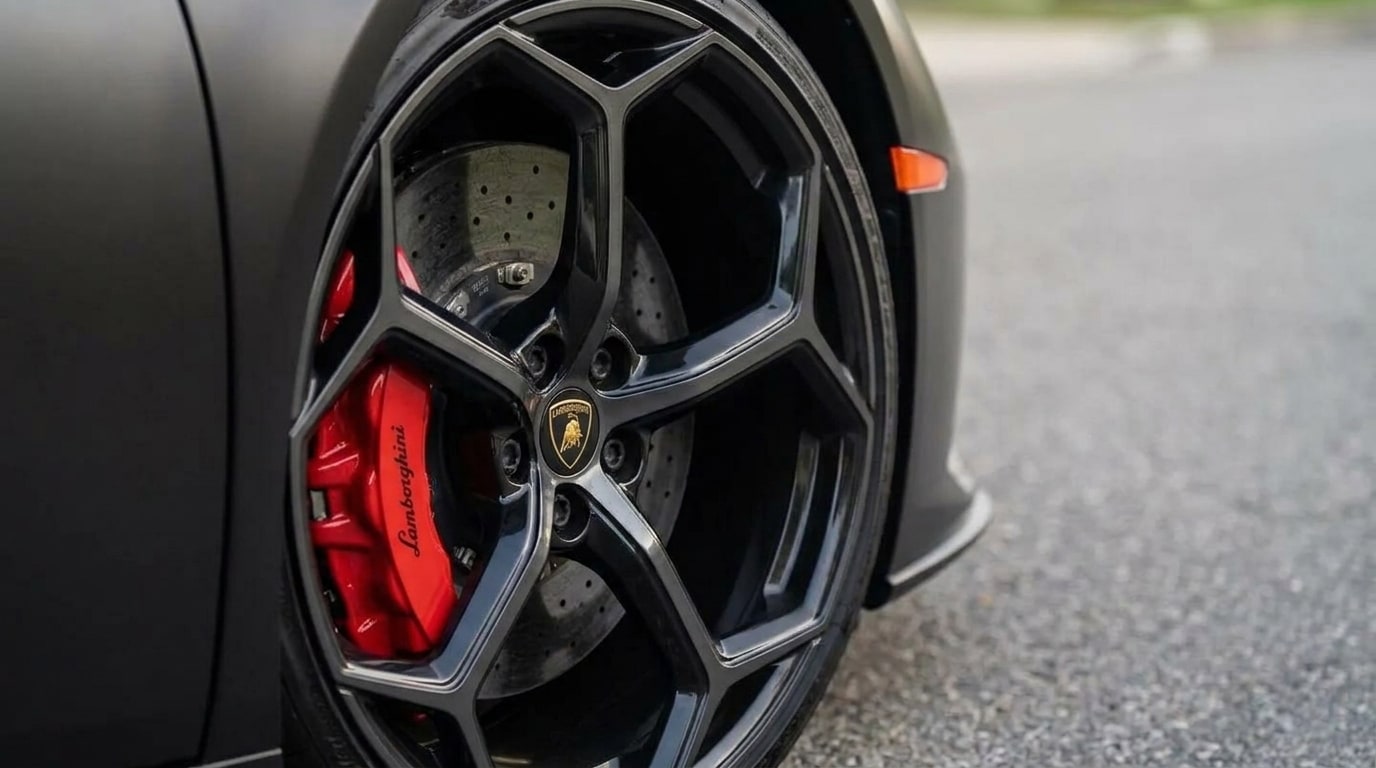 Red brake caliper behind the spokes of the matte black Lamborghini Huracan wheel