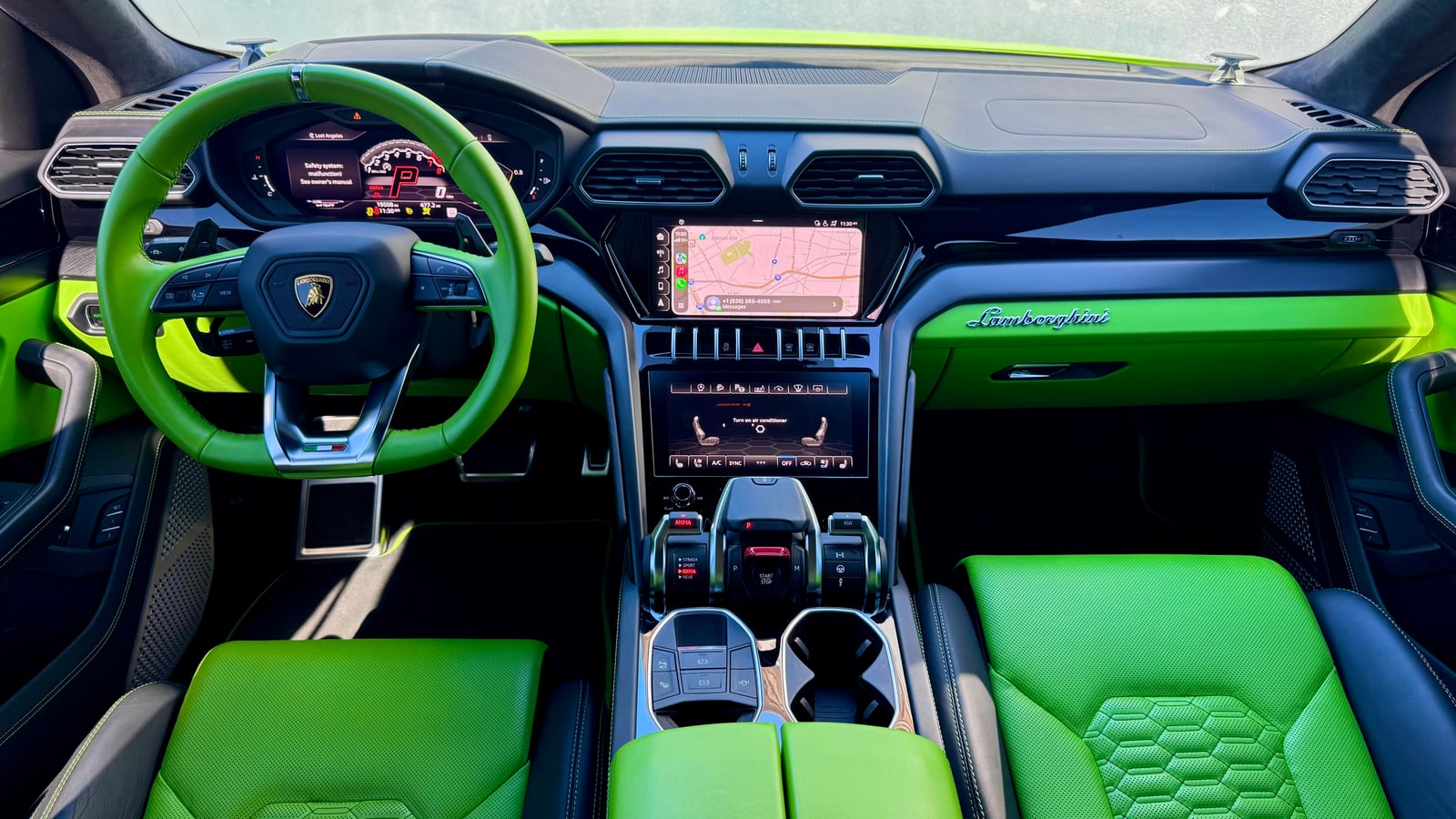 Dashboard of the green Lamborghini Urus: green wheel, twin screens and the Lamborghini script across the fascia