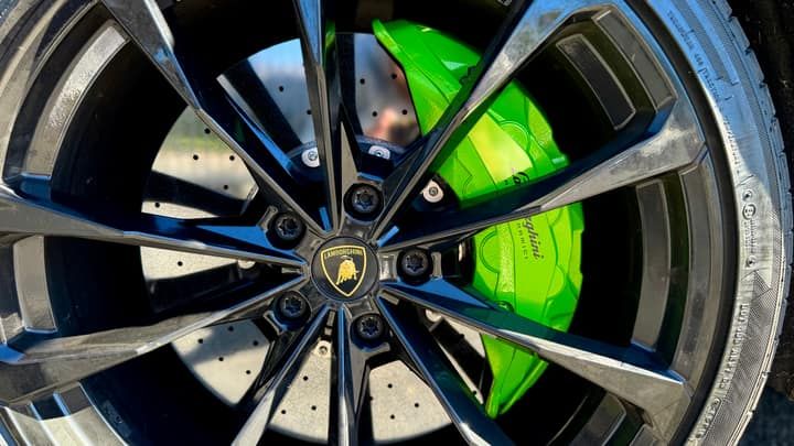 Green brake caliper and carbon-ceramic disc behind a Lamborghini Urus wheel