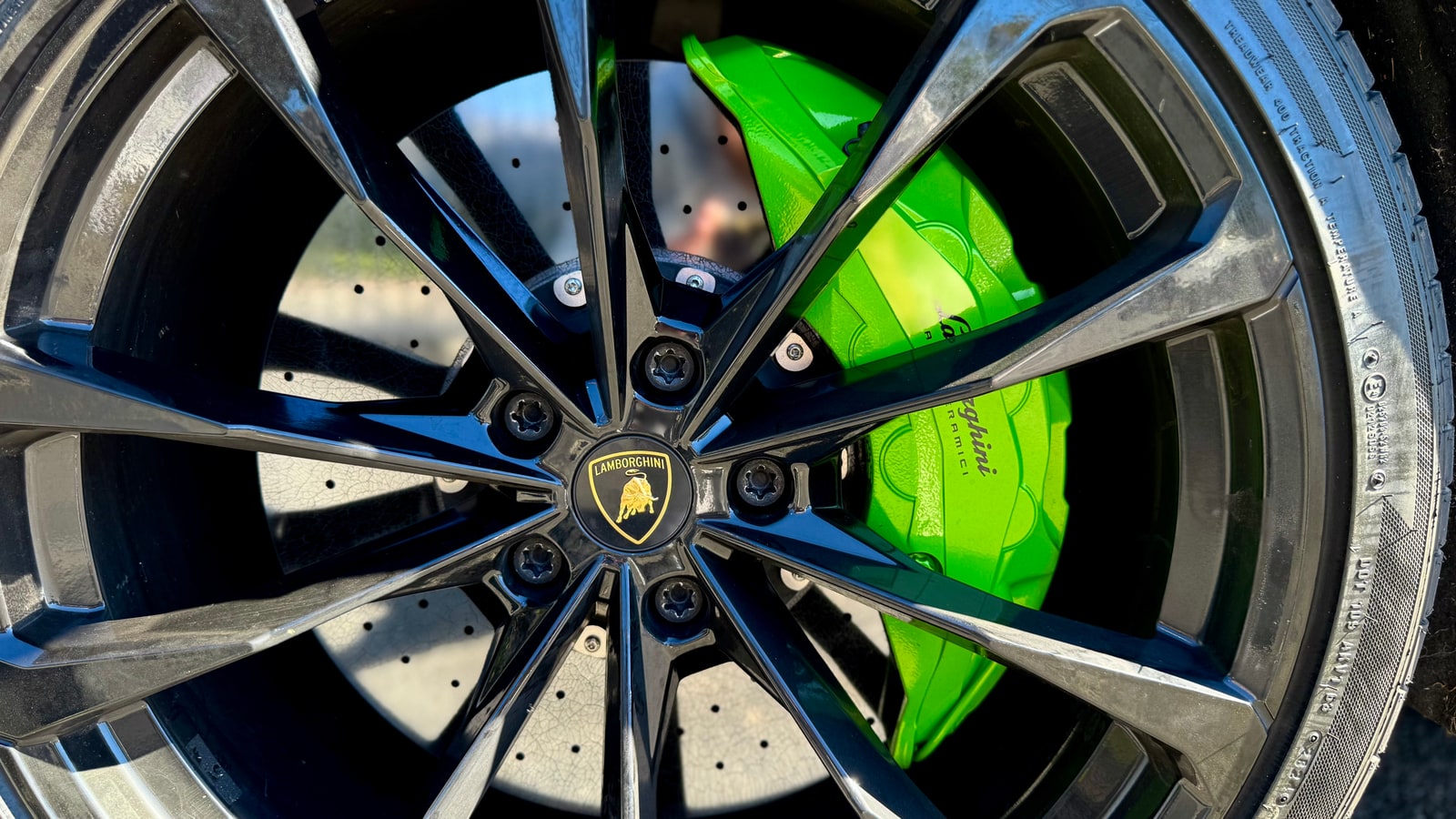 Wheel of the Lamborghini Urus with a green brake caliper and the crest on the centre cap