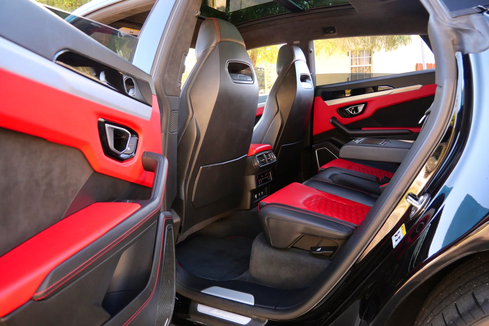 Red leather cabin of the black Lamborghini Urus seen through the rear door