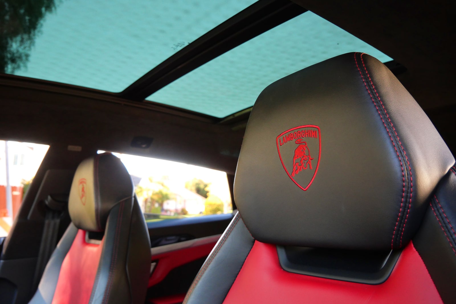 Panoramic roof above a red headrest with the embroidered Lamborghini crest