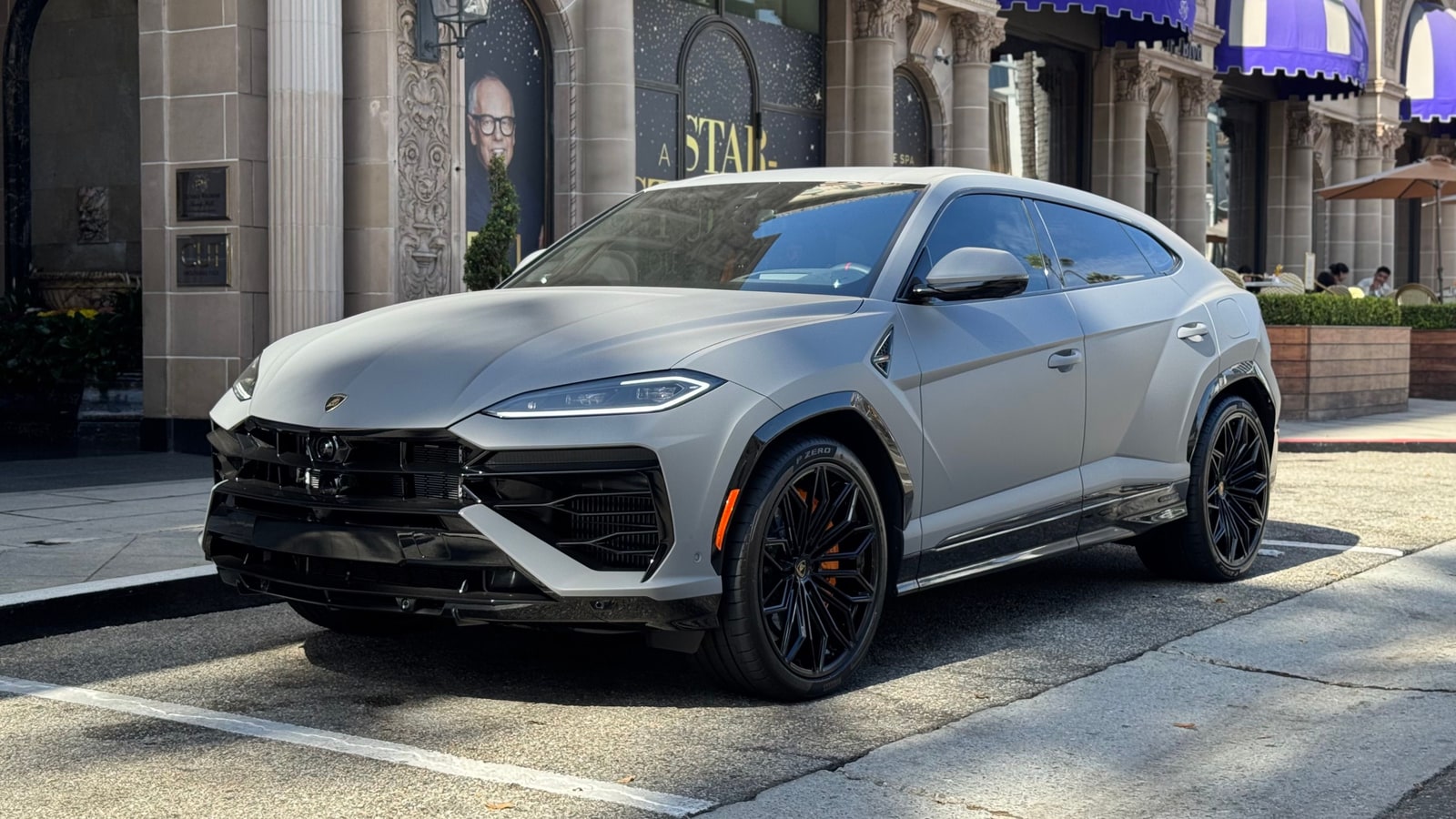 Matte grey Lamborghini Urus SE on a Beverly Hills street, front three-quarter view showing the new hood and headlights