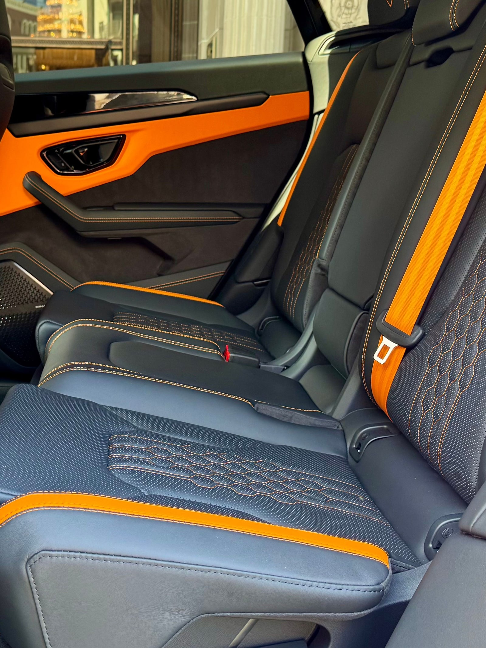 Rear bench of the Lamborghini Urus SE with orange seat belts