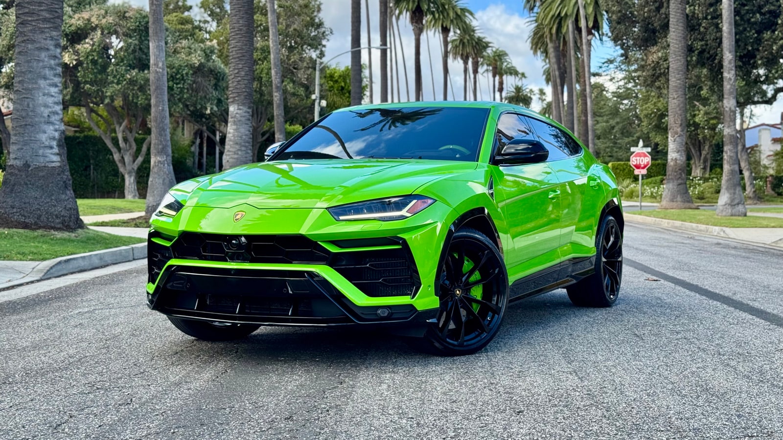 Verde Mantis green Lamborghini Urus from a front three-quarter on a palm-lined Beverly Hills street