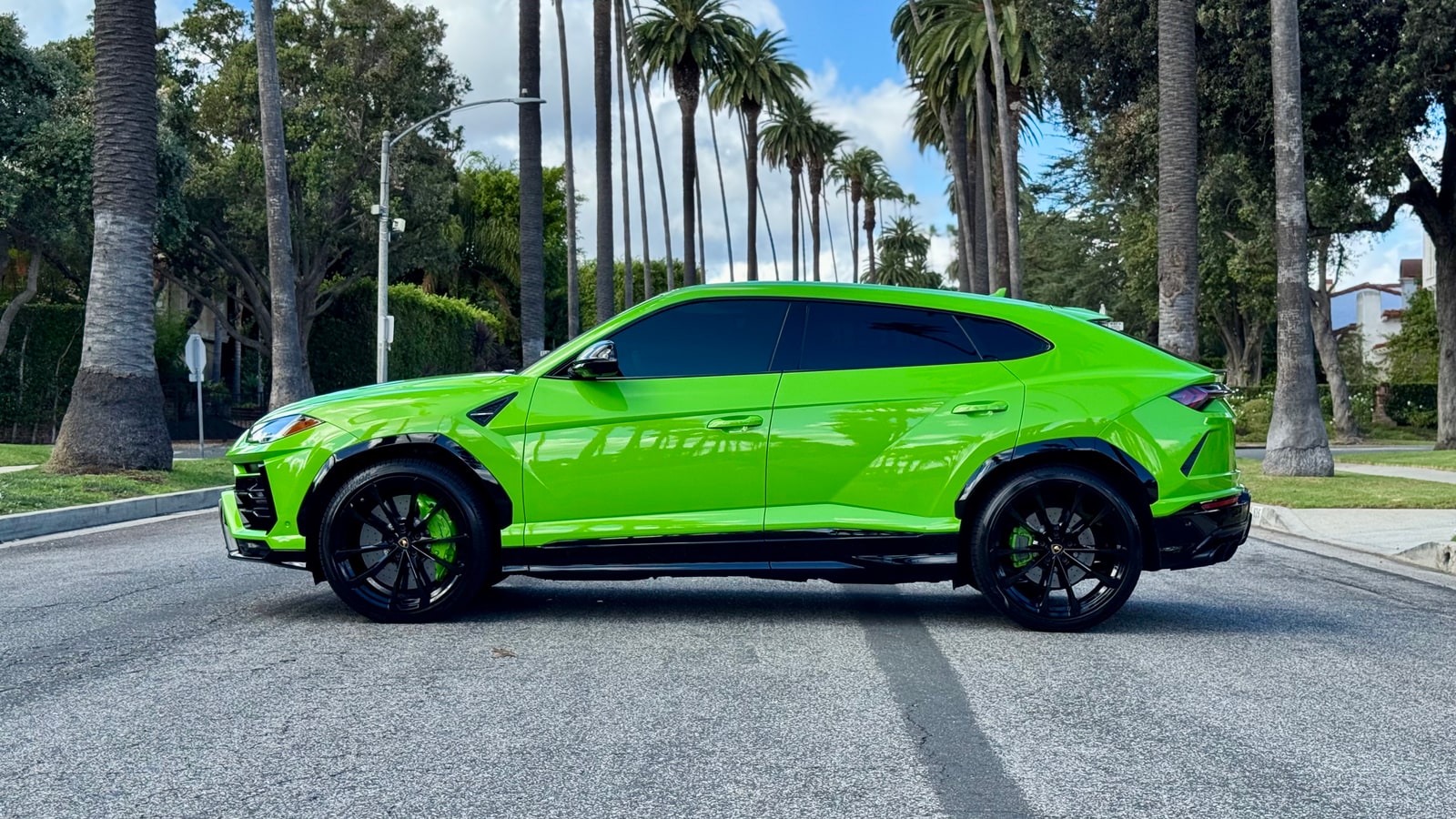 Green Lamborghini Urus in profile with black wheels