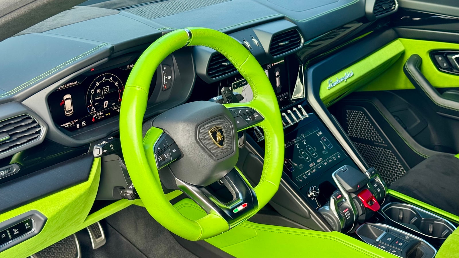 Green leather steering wheel rim of the Lamborghini Urus seen through the open door