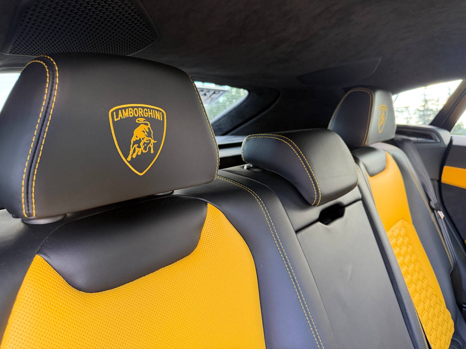 Headrest of the yellow Lamborghini Urus with the embroidered crest above a yellow seat
