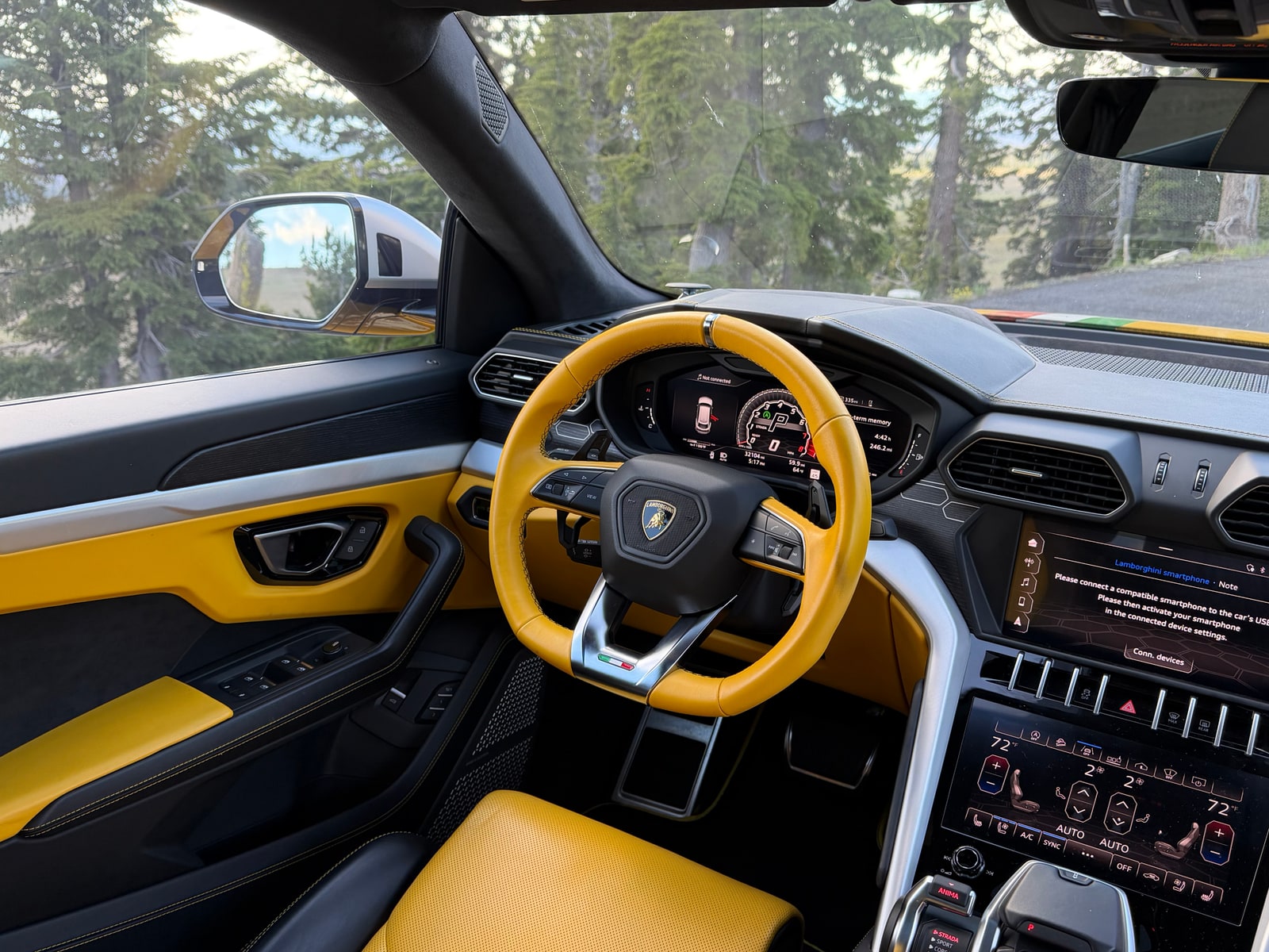 Yellow steering wheel and dashboard of the Lamborghini Urus with the road ahead