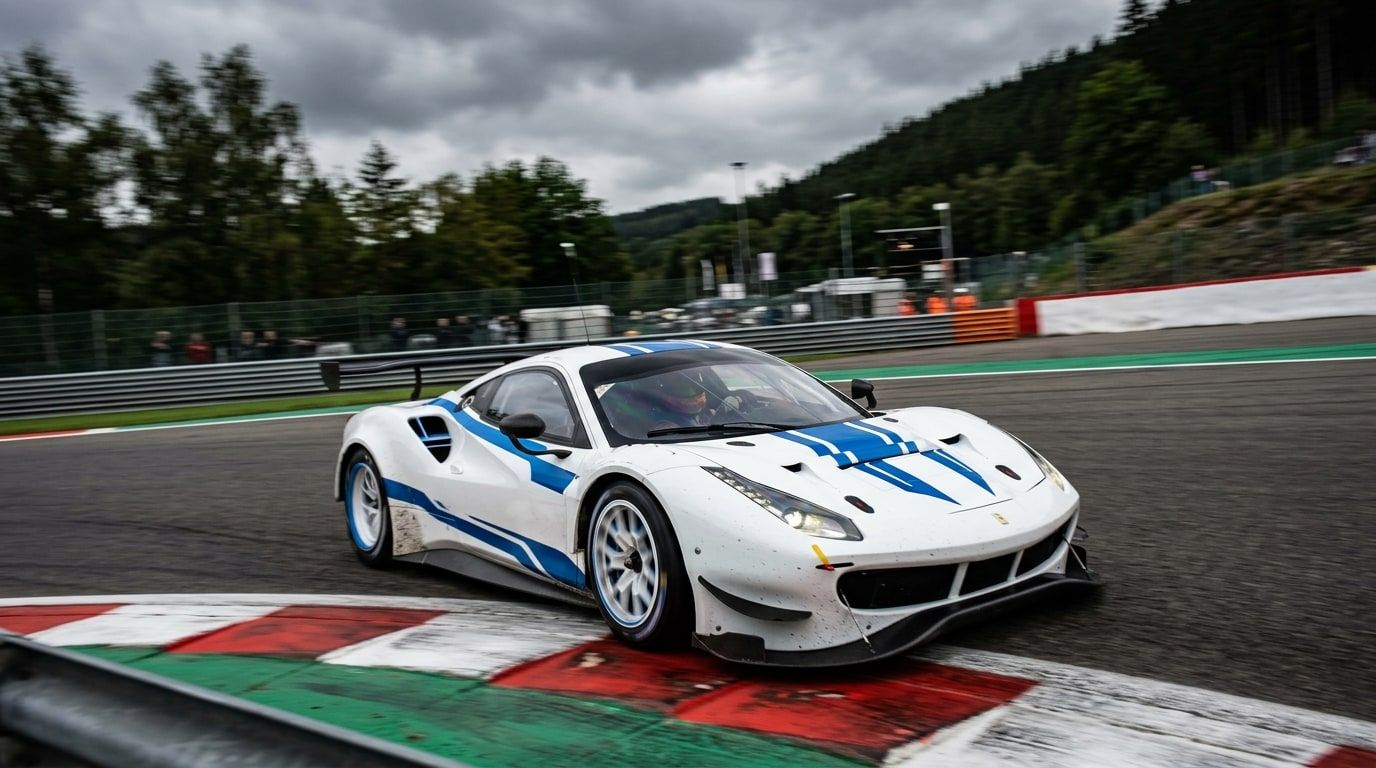 White and blue GT racing car cornering on a circuit, front three-quarter view from outside the corner