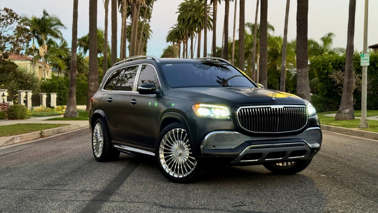 Matte black Maybach GLS 600 from a front three-quarter on a palm-lined Los Angeles street at dusk
