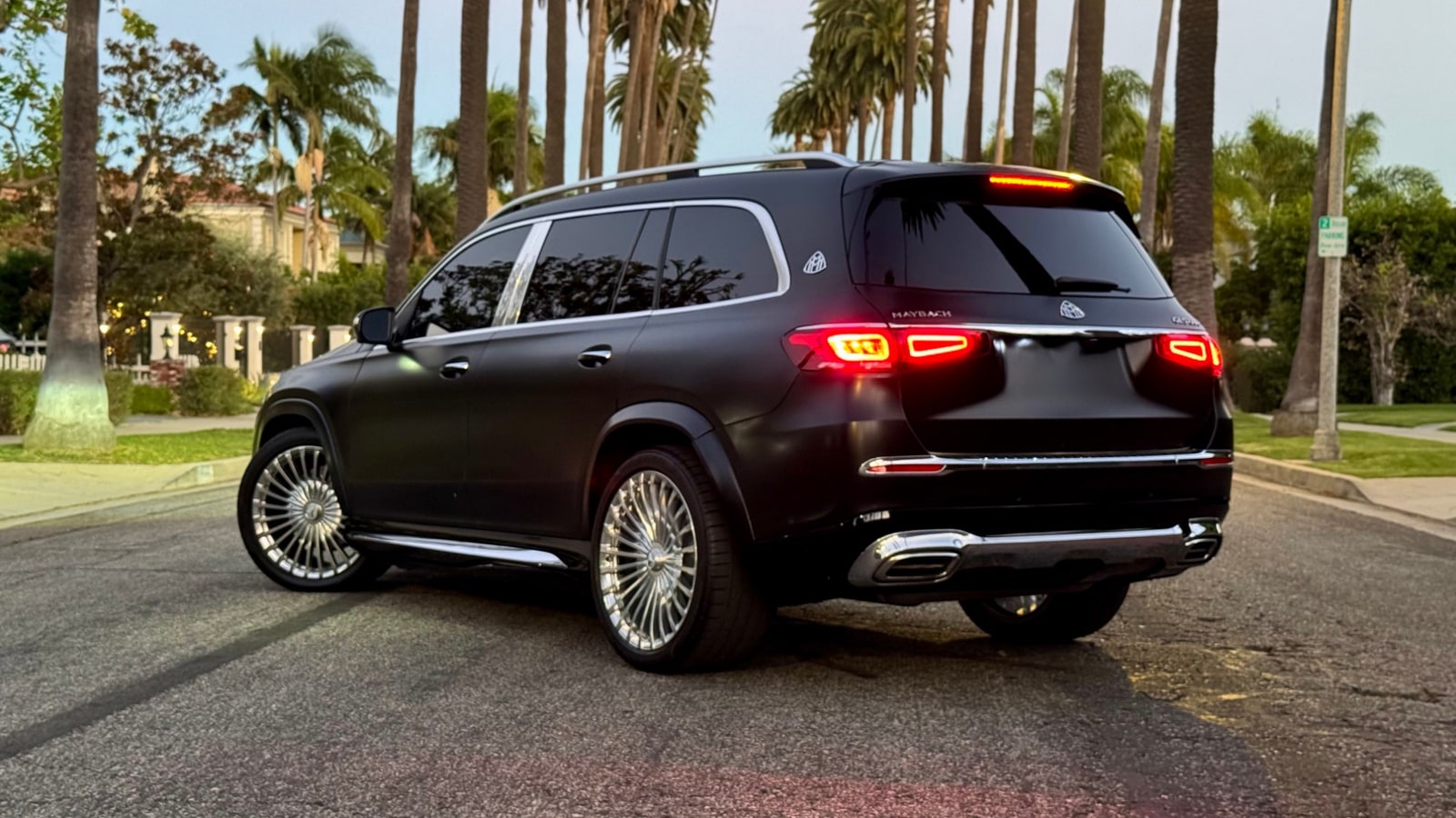 Matte black Maybach GLS 600 from the rear three-quarter with its tail lamps lit