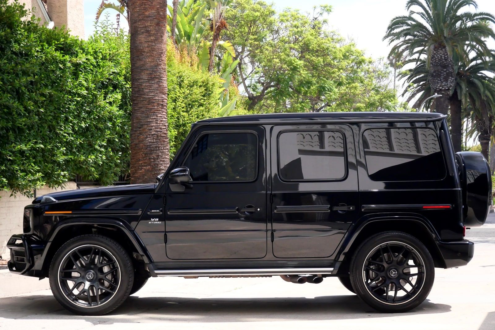 Black Mercedes-AMG G 63 from the rear three-quarter on a palm-lined Los Angeles street