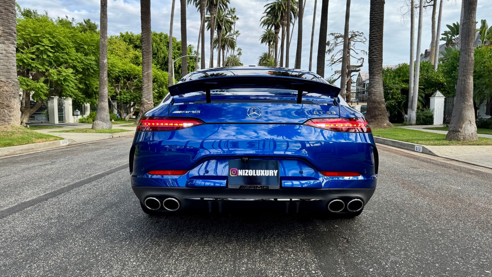 Blue Mercedes-AMG GT 53 from straight behind on a palm-lined street