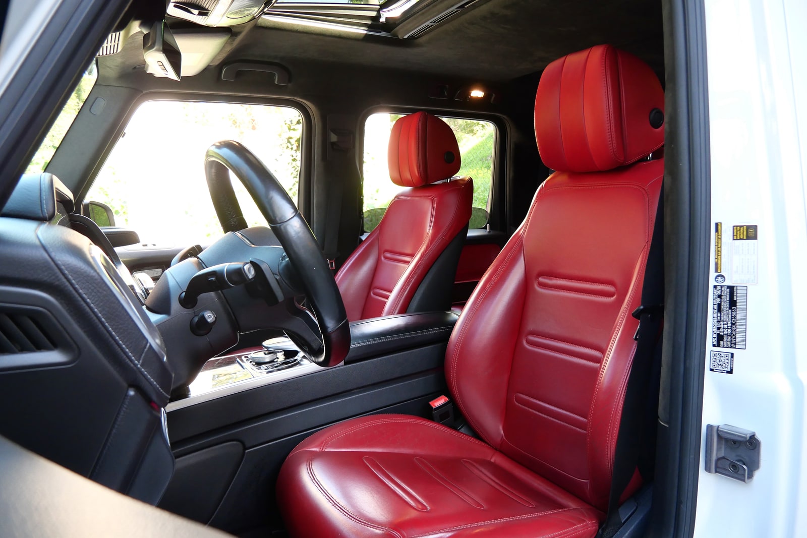 Red leather cabin of the white Mercedes-Benz G 550 seen through the driver's door