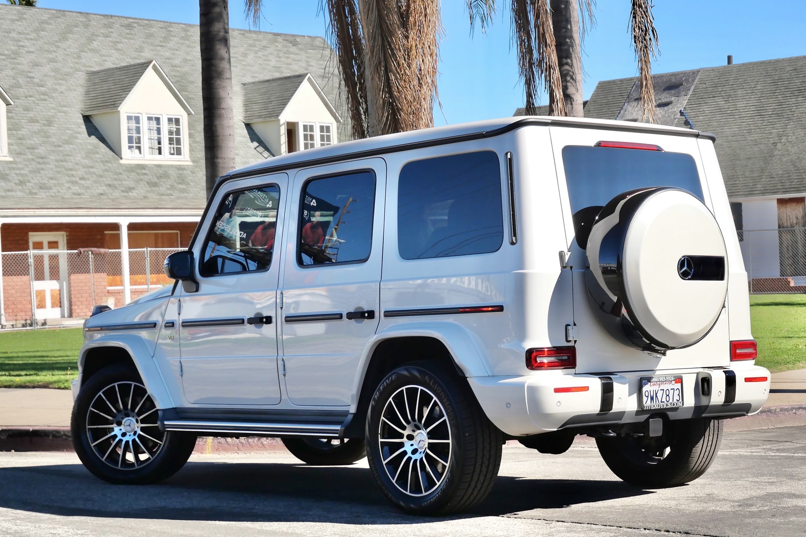 White Mercedes-Benz G 550 from the rear three-quarter with the spare wheel on the tailgate