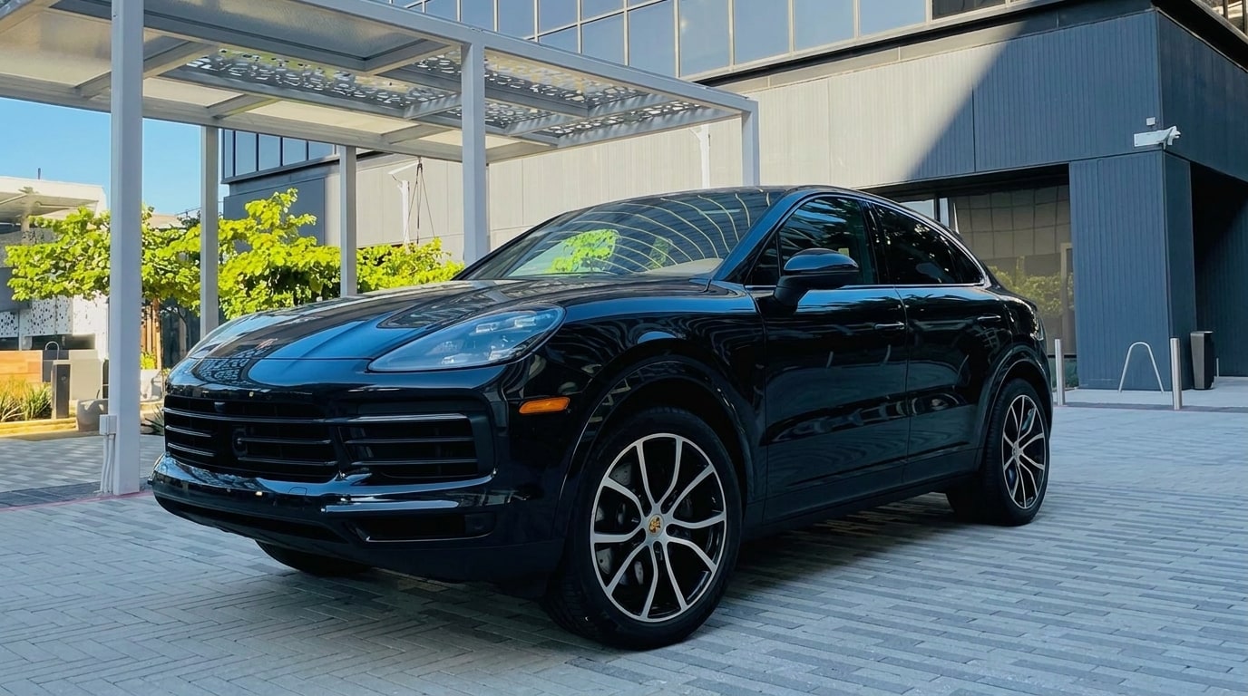 Black Porsche Cayenne Coupé in the forecourt of a glass office tower in Culver City, front three-quarter view