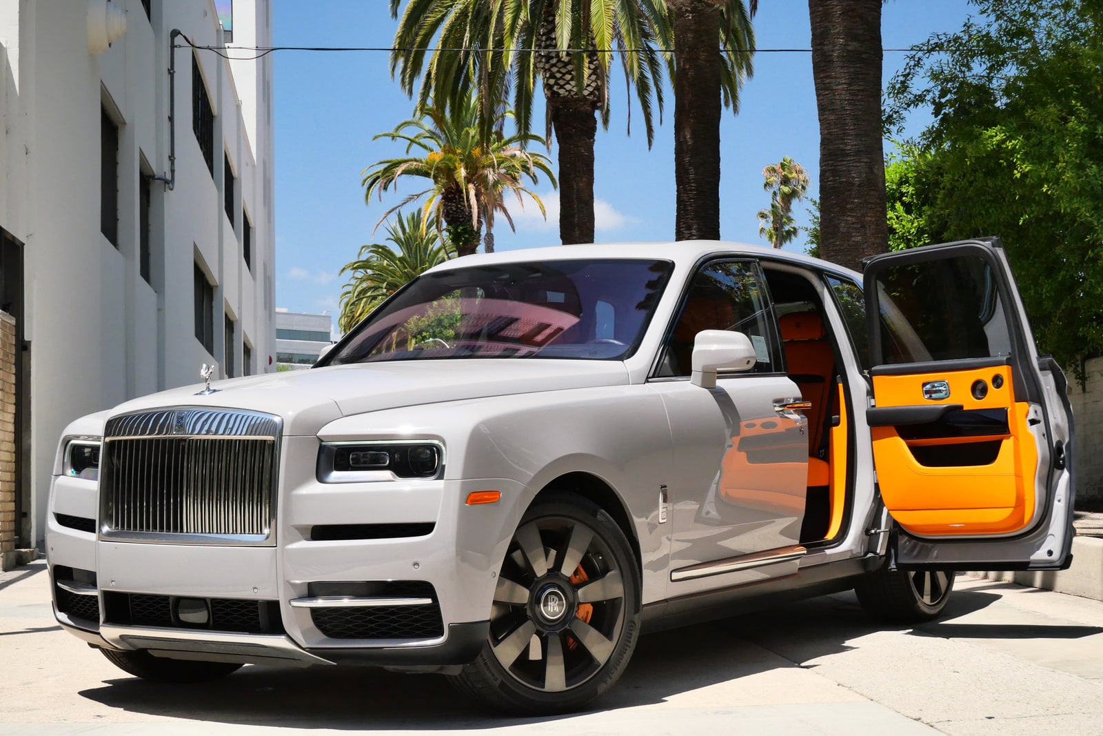 White Rolls-Royce Cullinan with its coach doors open showing the orange interior