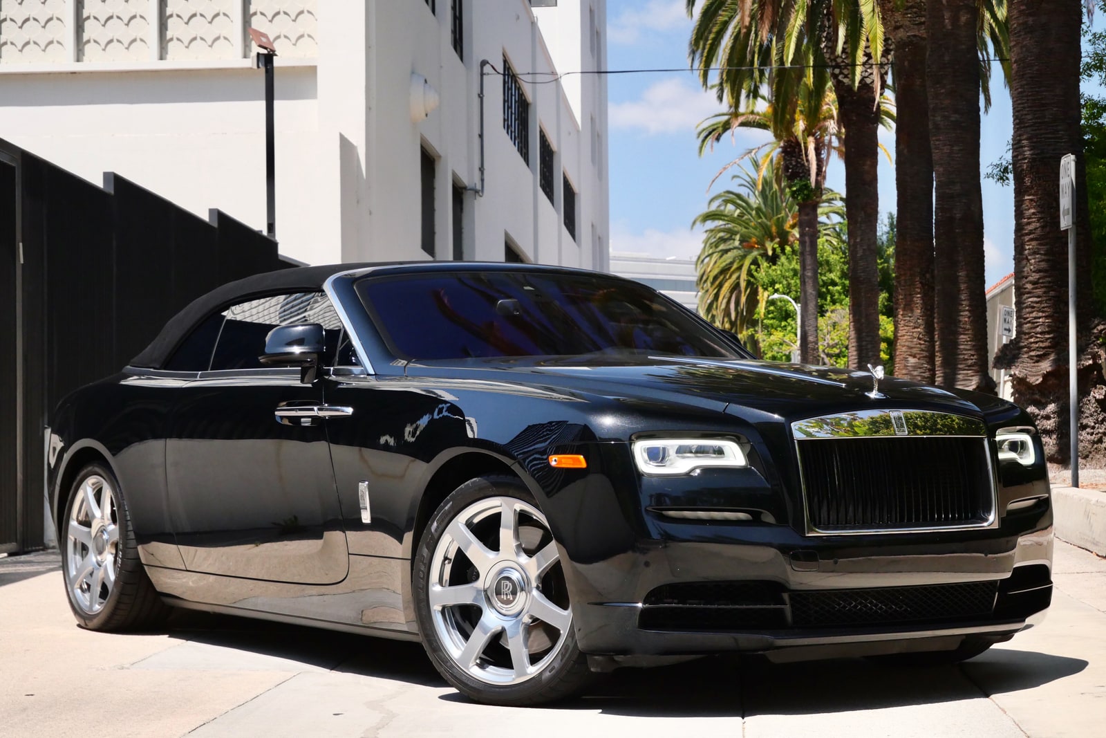 Black Rolls-Royce Dawn convertible with the roof down, seen from the front three-quarter