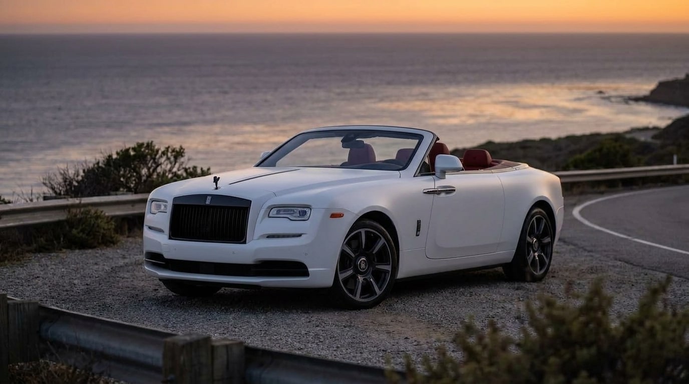 Matte white Rolls-Royce Dawn on the coast road above the Pacific at dusk